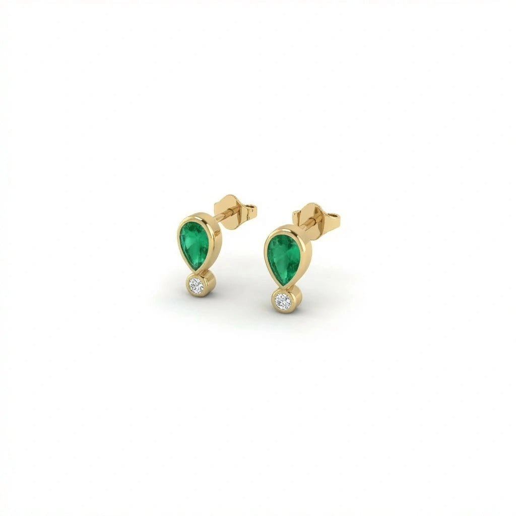 Elyra emerald drop stud earrings in solid yellow gold with pear cut emerald and bezel set diamond accent