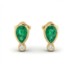 Close up of Elyra emerald drop stud earrings showing pear shaped emerald and round diamond accent in gold setting