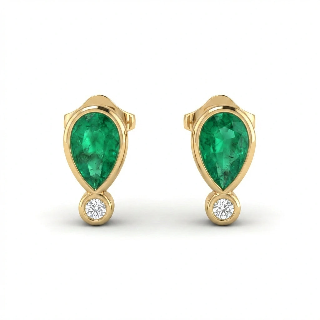 Close up of Elyra emerald drop stud earrings showing pear shaped emerald and round diamond accent in gold setting
