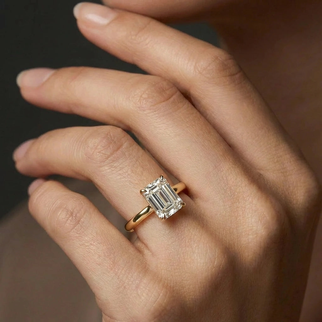 Woman wearing emerald-cut diamond hidden halo engagement ring in 14K yellow gold - lifestyle photo