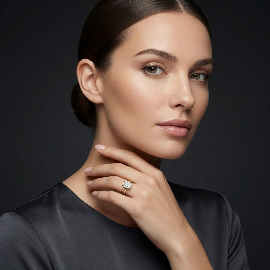 Woman wearing emerald-cut diamond hidden halo engagement ring in 14K yellow gold - elegant portrait lifestyle photo