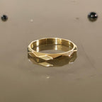 Close-up of 3mm faceted solid gold ring on reflective surface