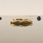 3mm faceted gold ring reflecting on a mirror surface