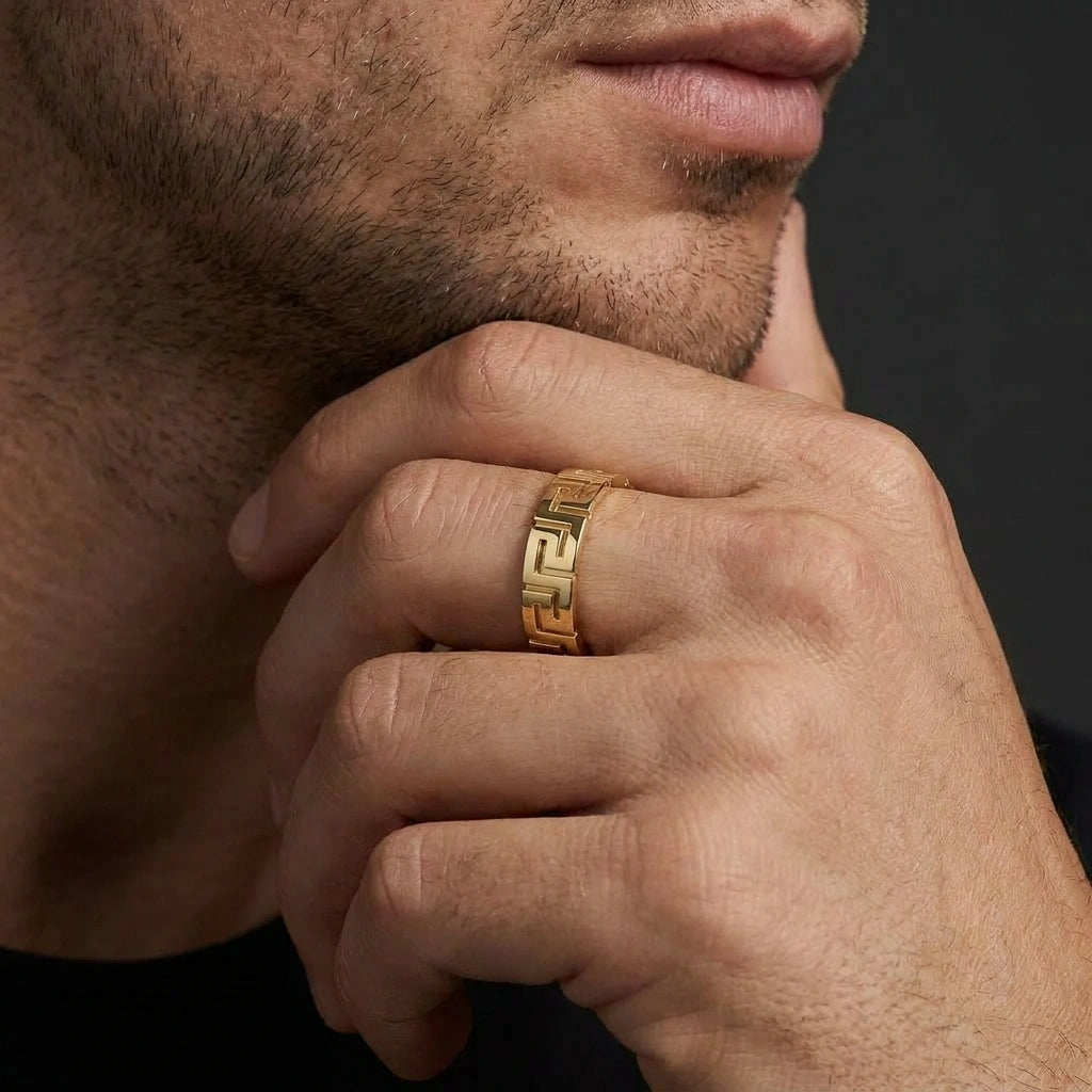 Man wearing solid 14K yellow gold Greek key meander wedding band on ring finger – lifestyle close-up showing full pattern detail