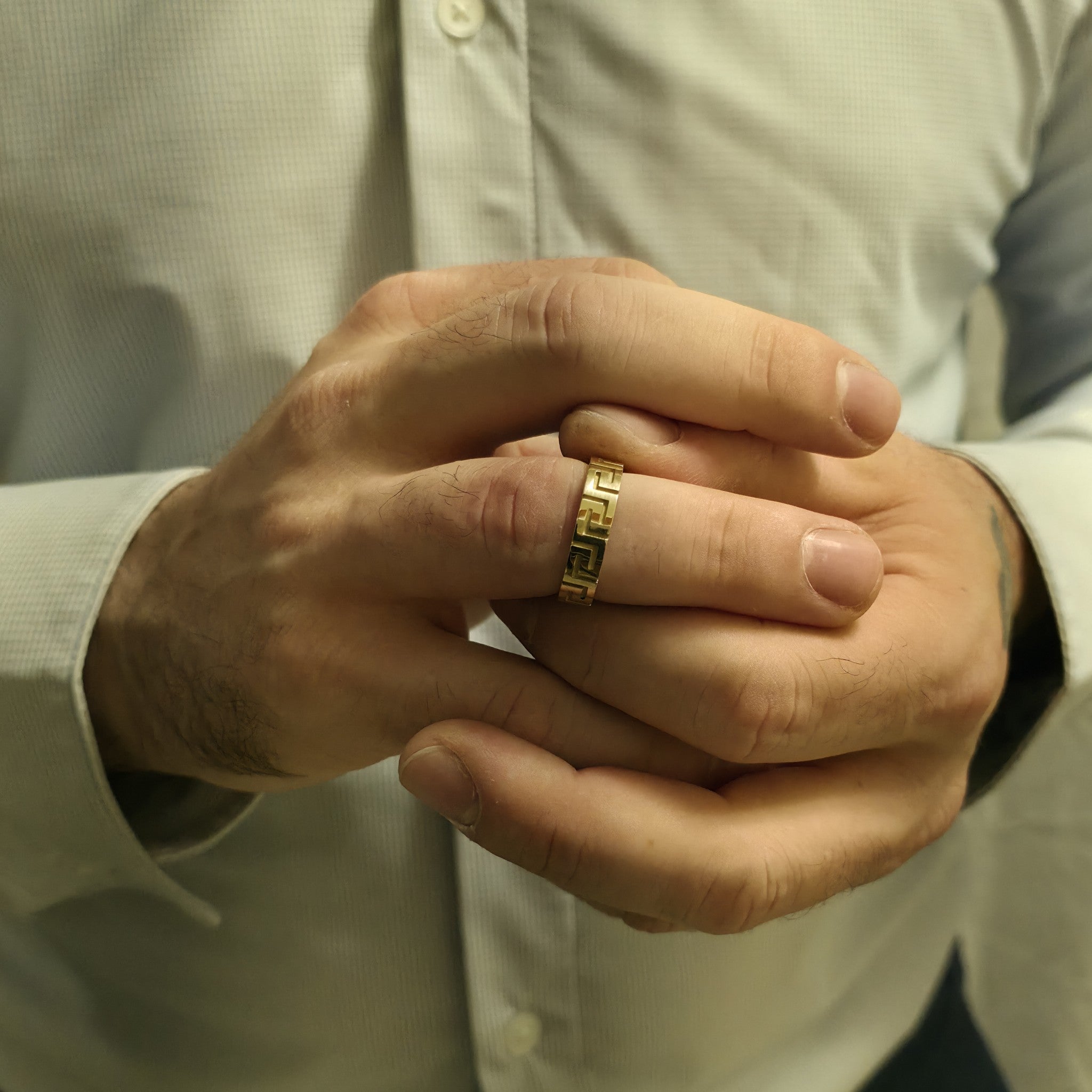 Greek key ring wedding band on man’s hand, dress shirt