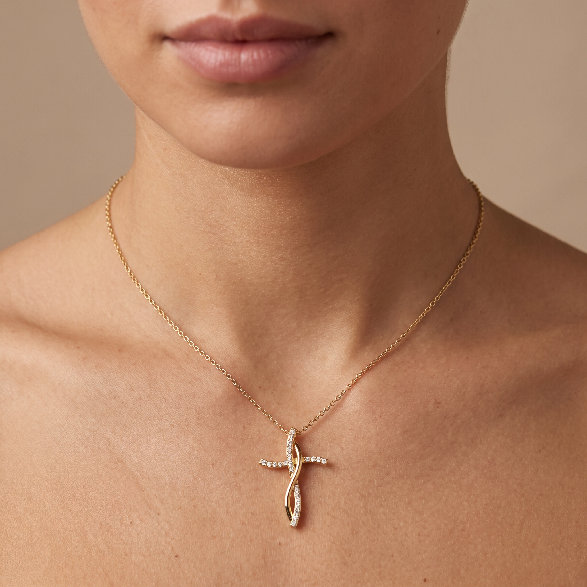 Woman wearing the infinity cross pendant in 14K yellow gold on a fine cable chain at the neckline