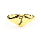 J initial cursive signet ring in polished 14K gold on a soft beige background.