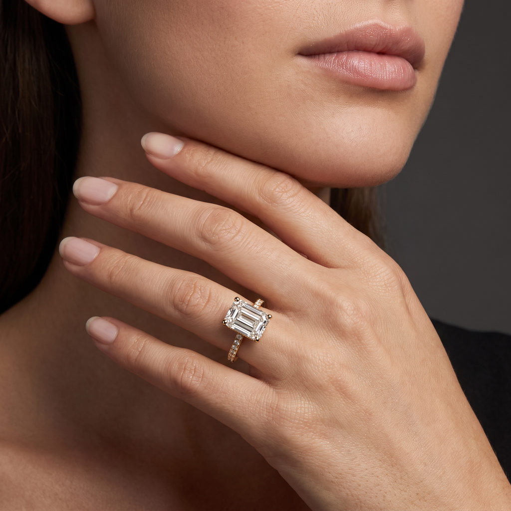 Hand wearing an emerald cut Lab-Grown Diamond pavé engagement ring in 14K yellow gold