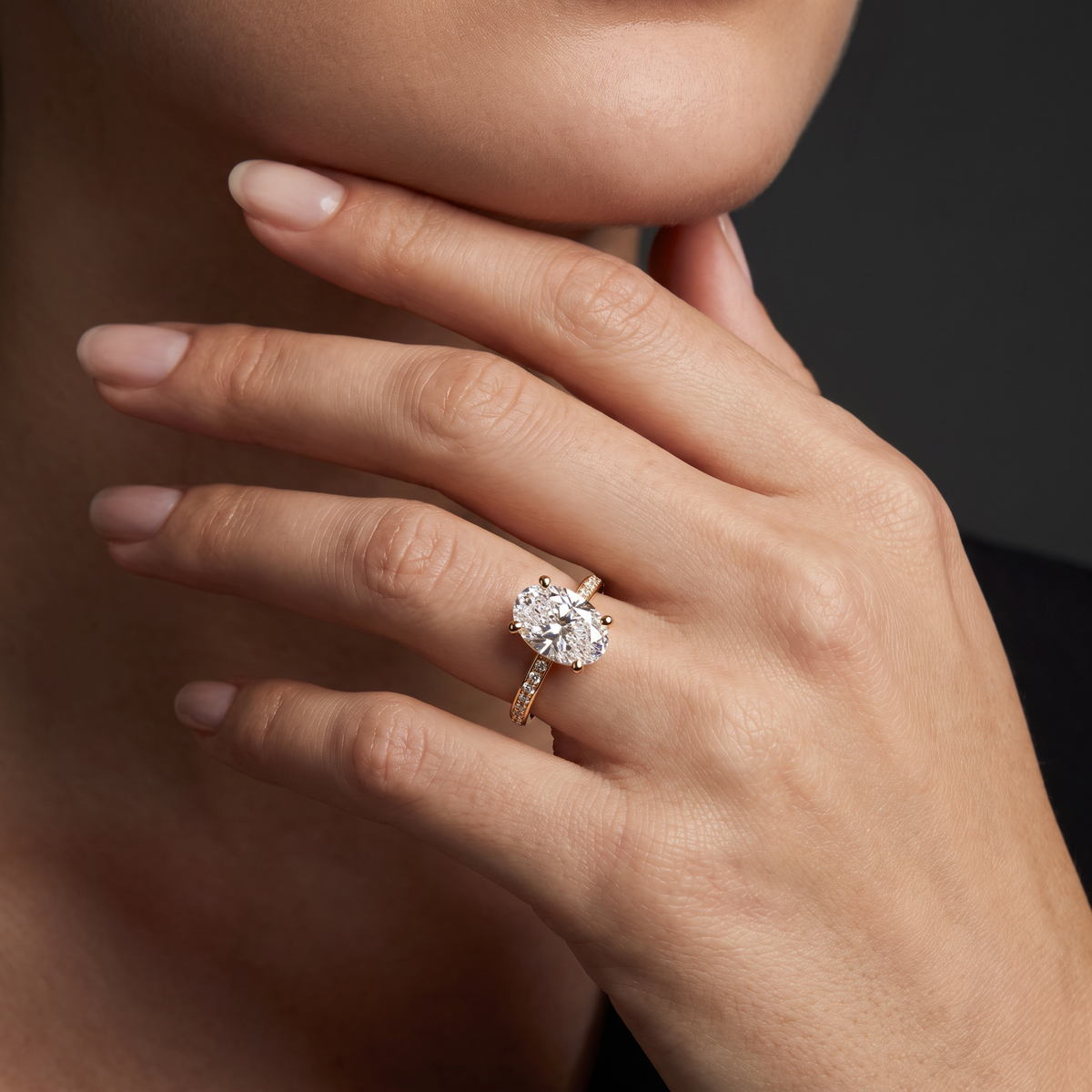 Hand wearing an oval Lab-Grown Diamond pavé engagement ring in solid 14K gold