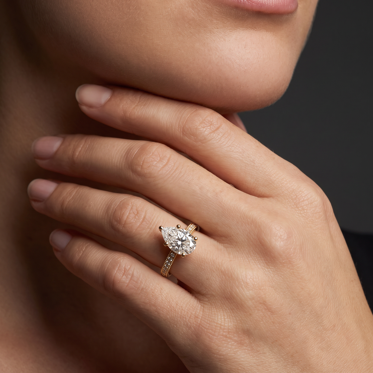 Hand wearing a pear-shaped Lab-Grown Diamond milgrain pavé engagement ring in 14K yellow gold