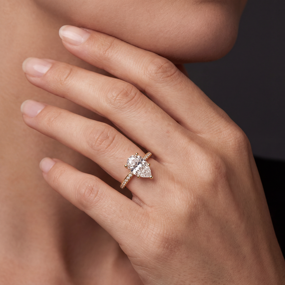 Hand wearing a pear-shaped Lab-Grown Diamond pavé engagement ring in 14K yellow gold