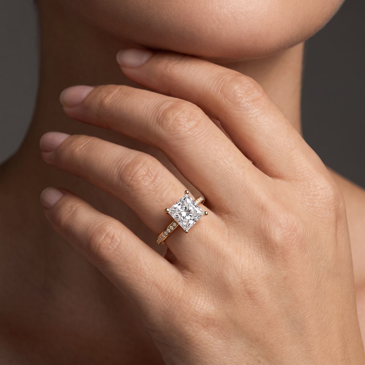 Hand wearing a princess cut Lab-Grown Diamond pavé engagement ring in 14K yellow gold