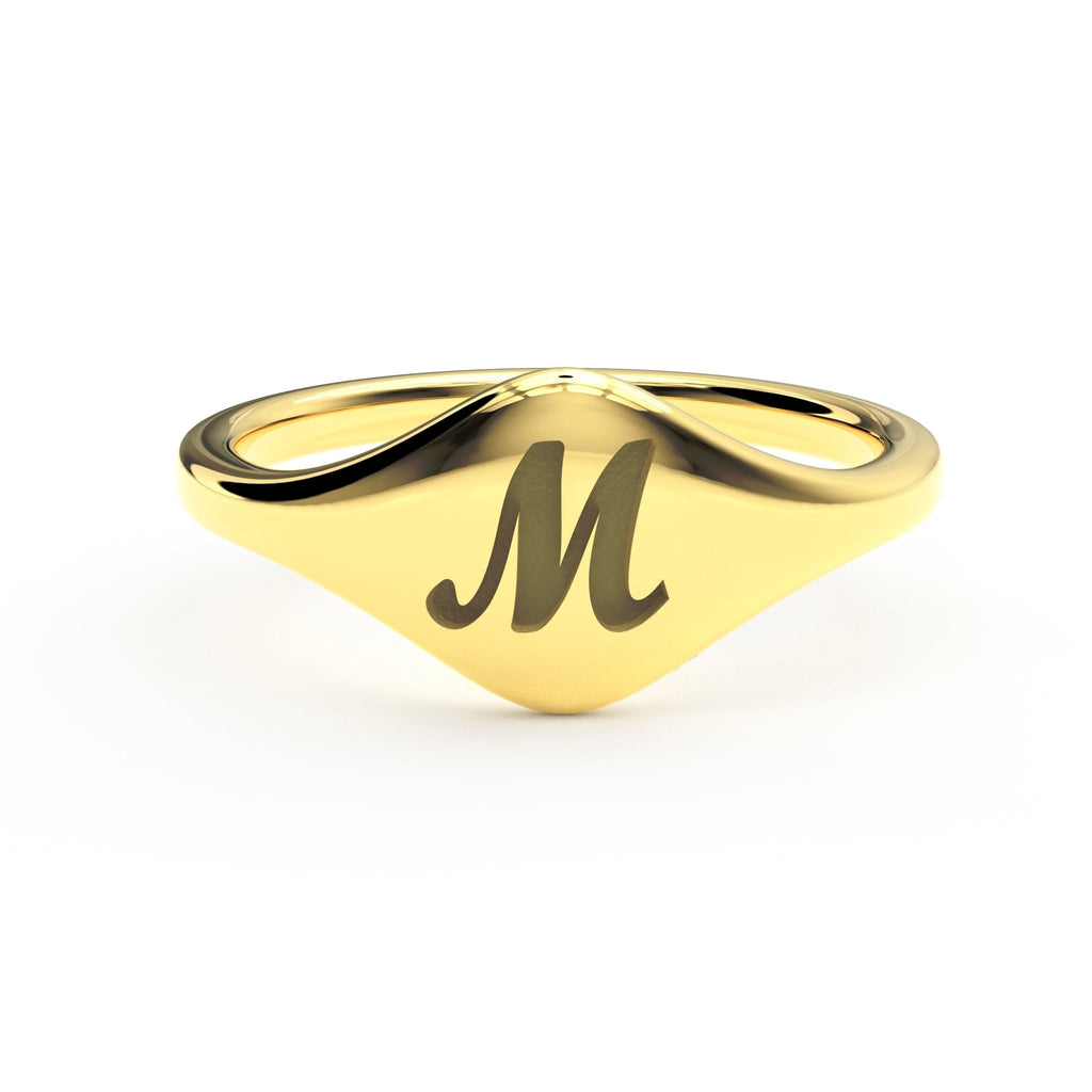 M initial cursive signet ring in polished 14K gold on a soft beige background.