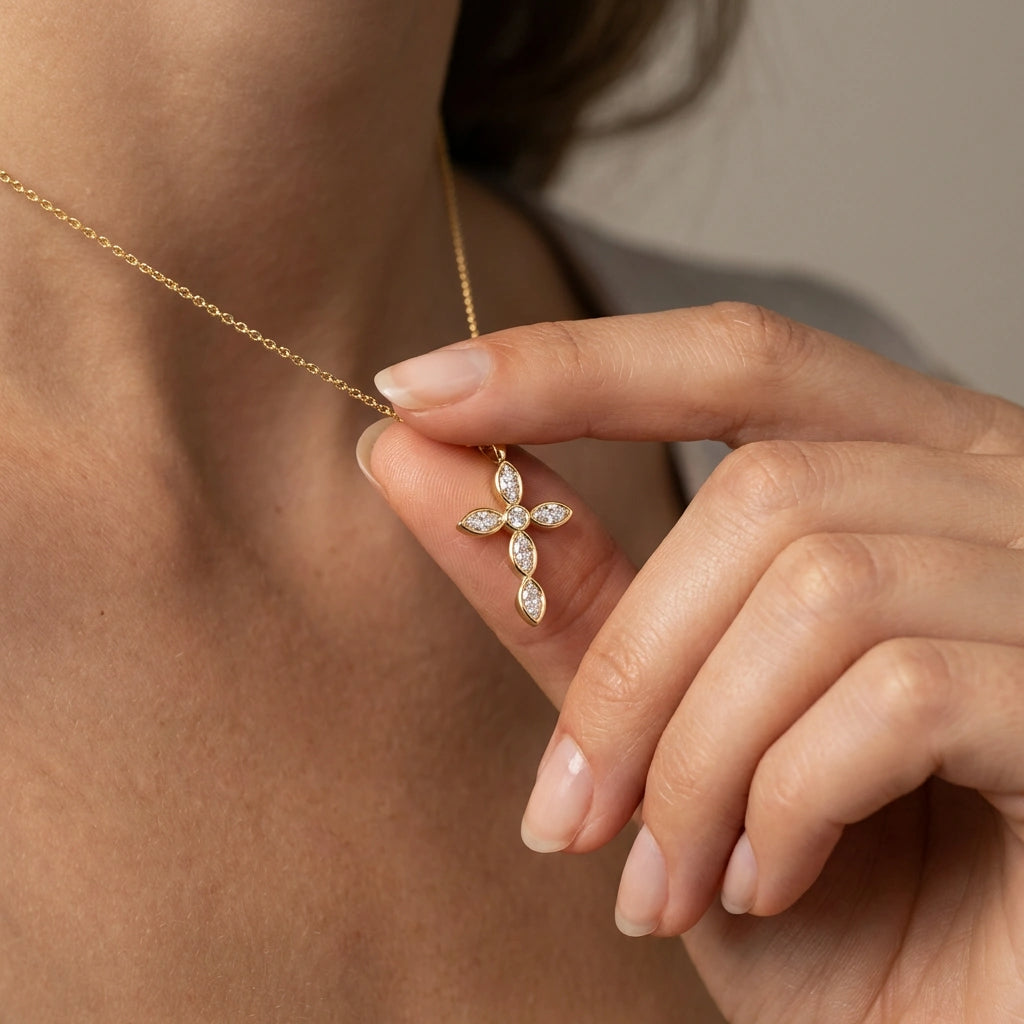 Close-up of woman holding 14K gold marquise diamond cross necklace showing center round diamond detail