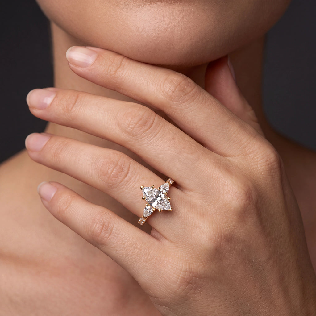Model wearing marquise Lab-Grown Diamond three-stone engagement ring with pear side stones in 14K gold — Black Pearl of Queens