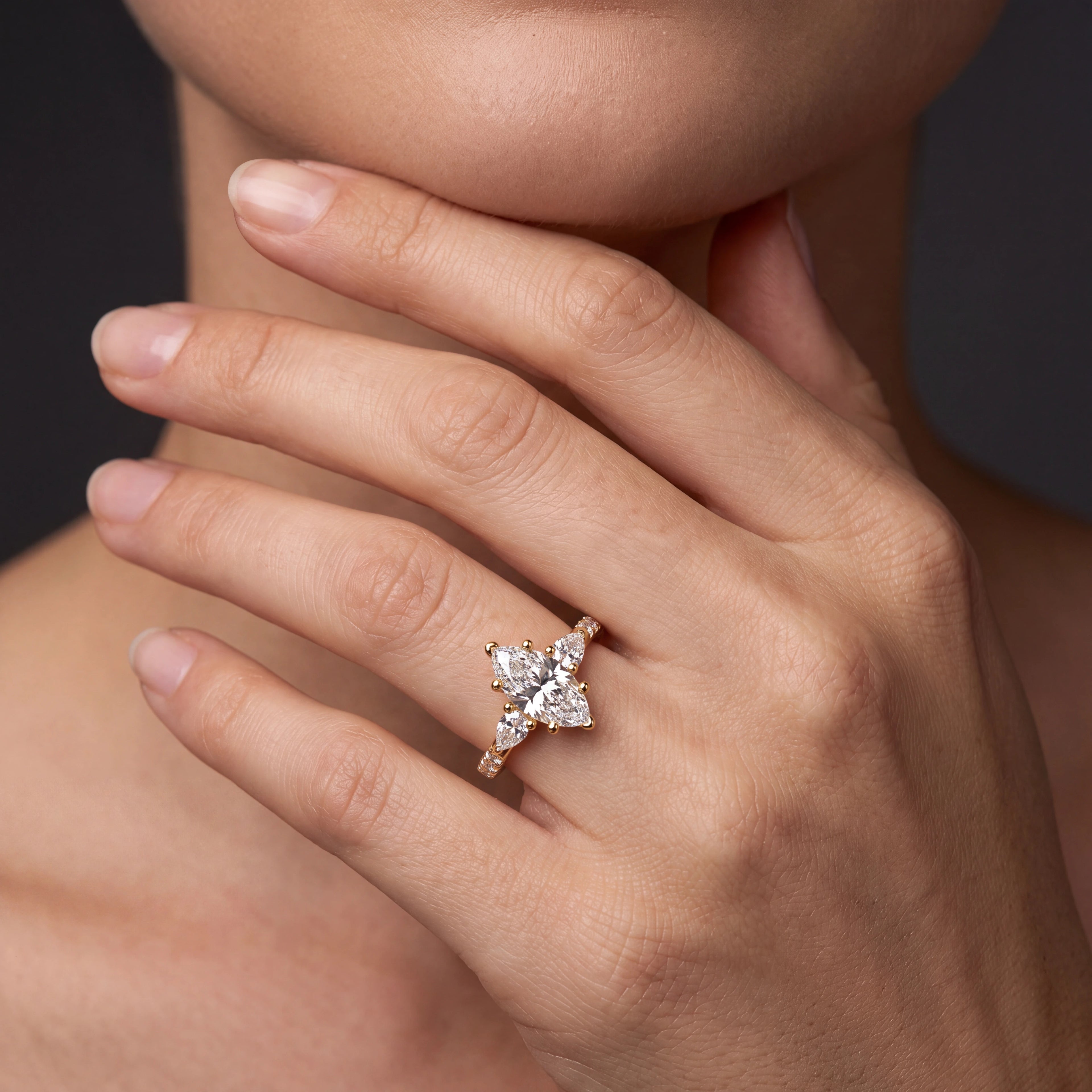 Model wearing marquise Lab-Grown Diamond three-stone engagement ring with pear side stones in 14K gold — Black Pearl of Queens