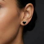 Noir Amora heart stud earrings in 14K yellow gold with black enamel worn by model close up portrait