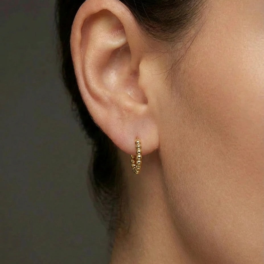 Woman wearing Orba Beaded Huggie Earrings in 14K gold, everyday minimalist hoop earrings