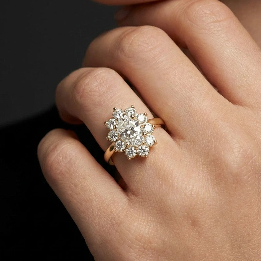 0.7ct oval diamond flower halo engagement ring on hand in 14K yellow gold - showing finger-flattering oval shape