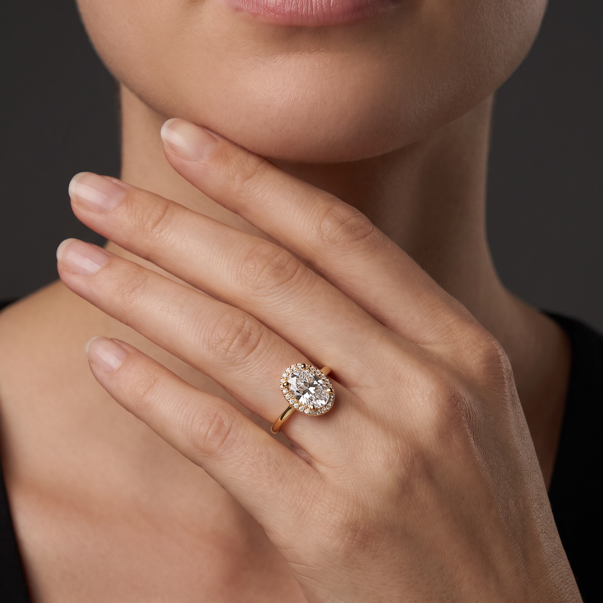 Woman wearing the oval halo engagement ring in 14K yellow gold, showing how the halo reads on the finger