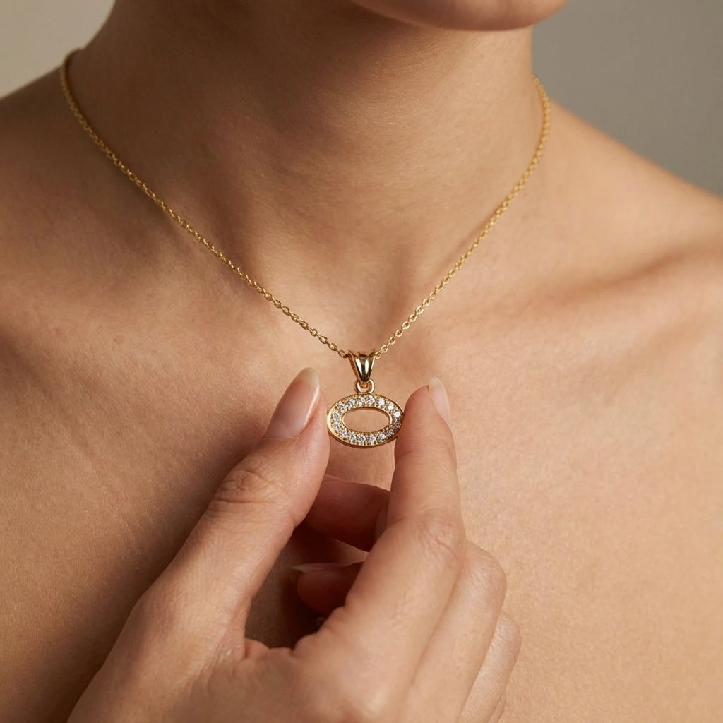 Close-up of oval pavé diamond pendant in 14K yellow gold worn on woman