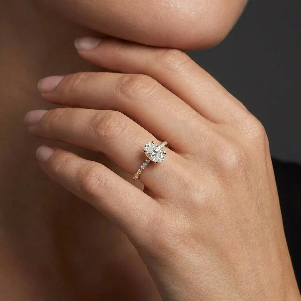 Woman wearing an oval lab-grown diamond pavé engagement ring in solid 14K yellow gold with a thin band setting