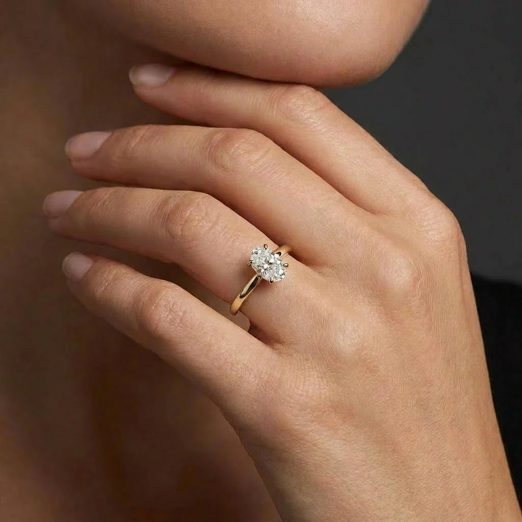 Woman wearing an oval solitaire ultra thin engagement ring in solid 14K yellow gold
