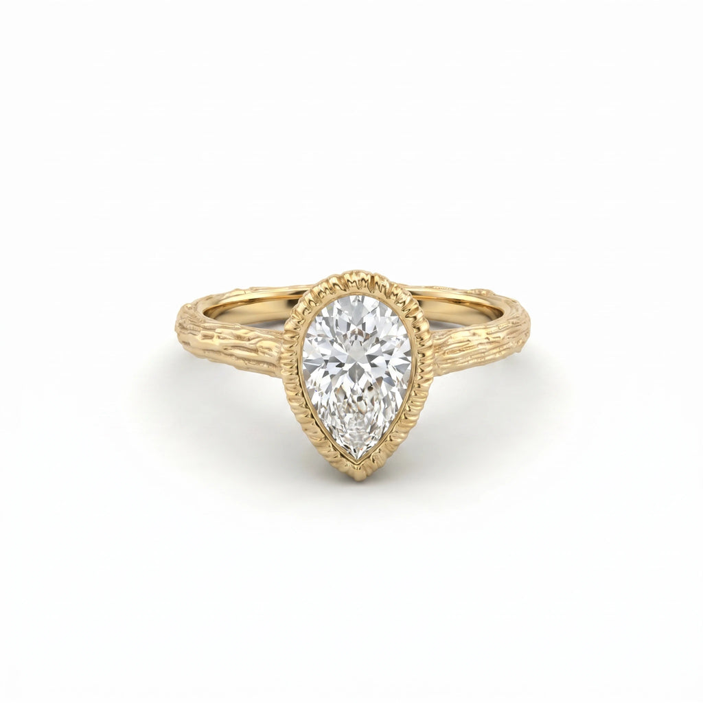 Pear Lab-Grown Diamond engagement ring, angled view of the bezel-set stone and bark-textured branch band in 14K yellow gold