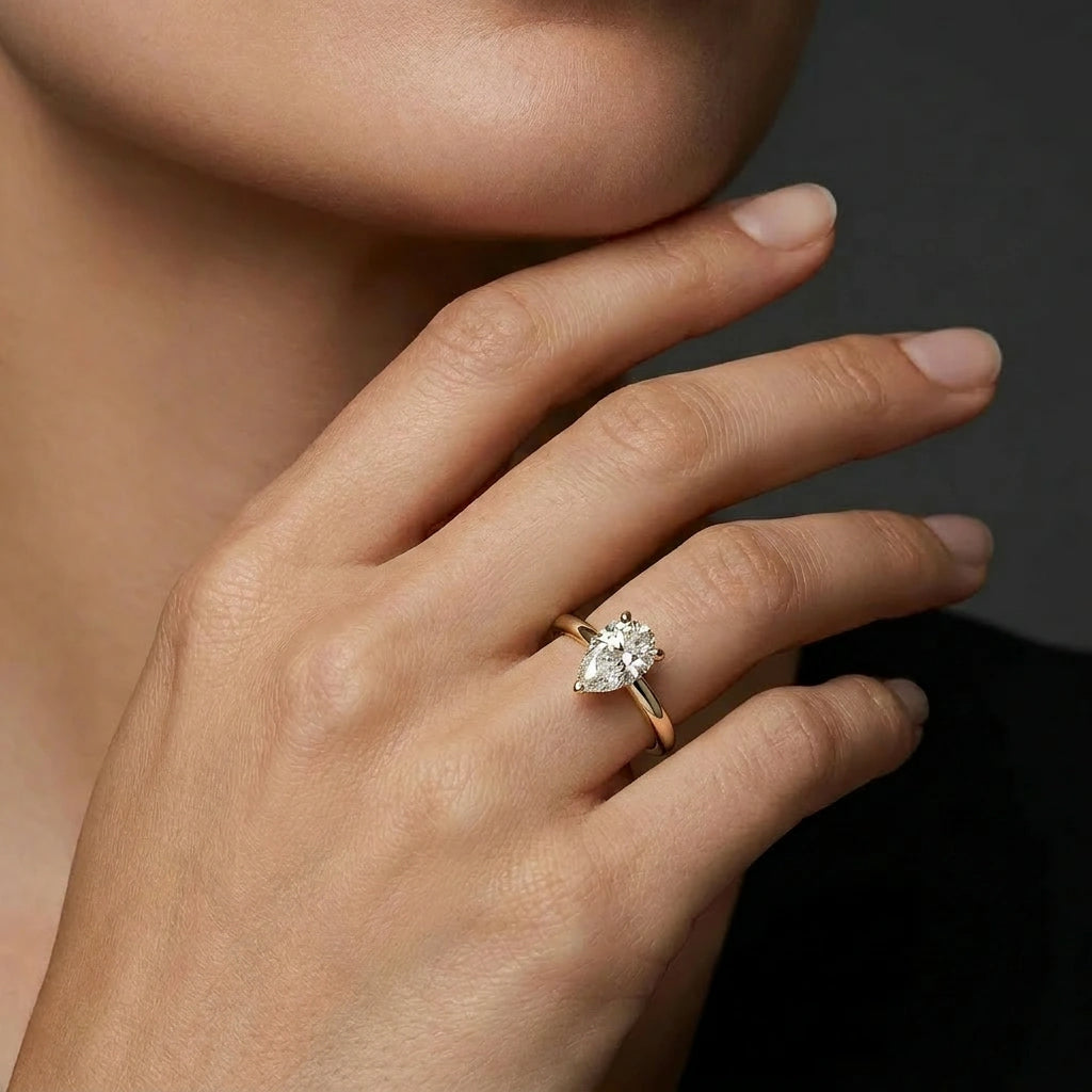 Woman wearing a pear solitaire ultra thin engagement ring in solid 14K yellow gold