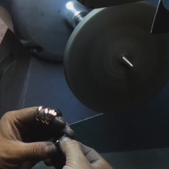 Jeweler hand-polishing a 14K plain gold wedding band for a high-gloss finish.