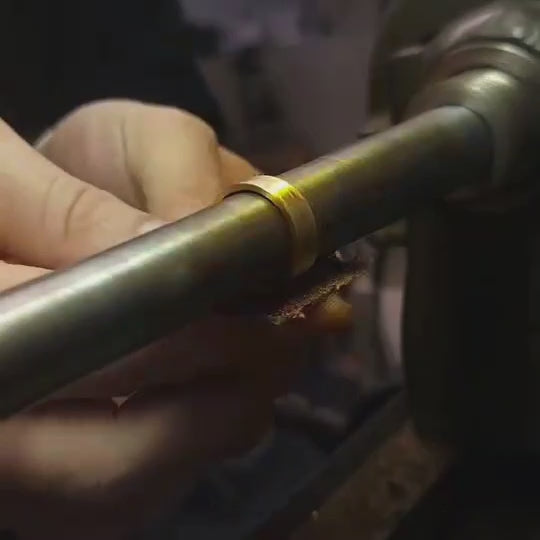 Video of an artisan hand-texturing a 14K gold wedding band, showing hammering and surface detailing during the crafting process.