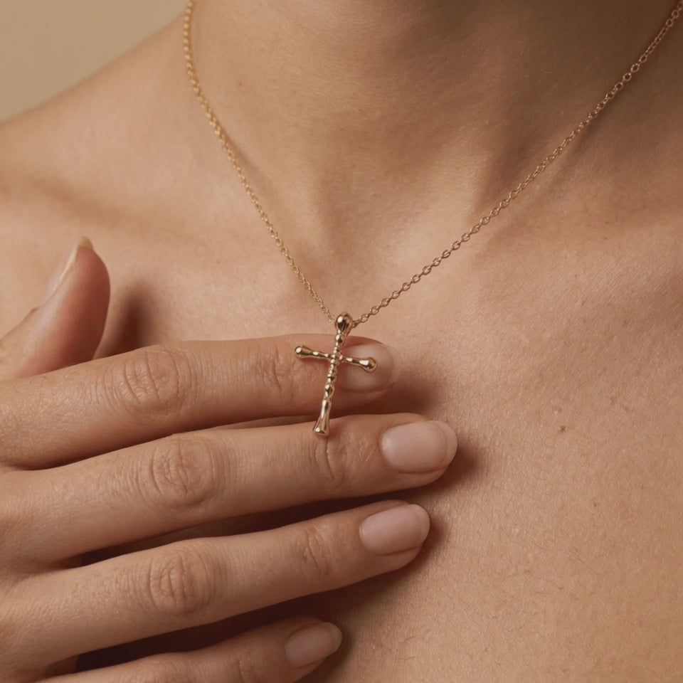 Close-up lifestyle video of woman wearing 14K gold Guardian cross necklace showing small beveled pendant detail
