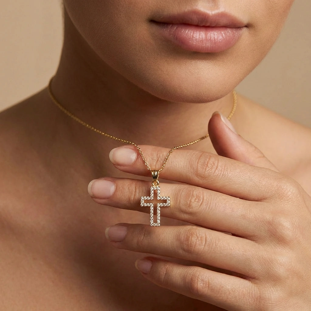 Close-up of 14K yellow gold Radiant pavé diamond cross necklace worn on model holding pendant