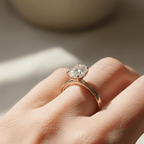 Side profile view of a woman wearing a true 1ct oval solitaire engagement ring in 14K yellow gold, vertical north–south orientation, UGC-style.