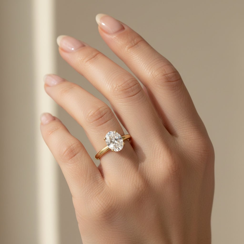 Woman wearing a 1ct oval solitaire engagement ring in 14K yellow gold, north–south orientation, UGC-style close-up.