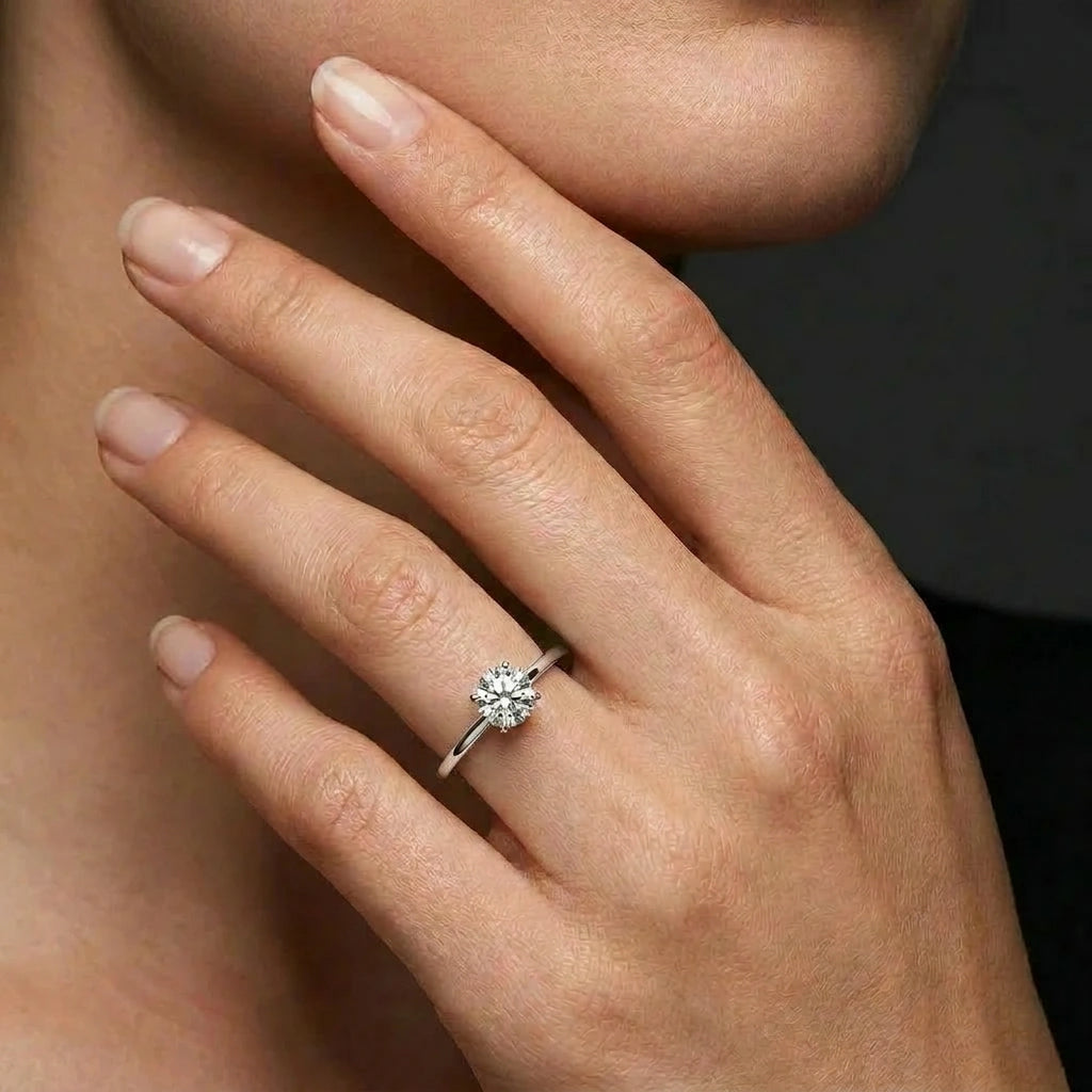 Woman wearing a round ultra thin solitaire engagement ring in solid 14K white gold