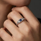 Woman wearing sapphire twisted rope three-stone ring - elegant portrait showing blue sapphire and diamonds