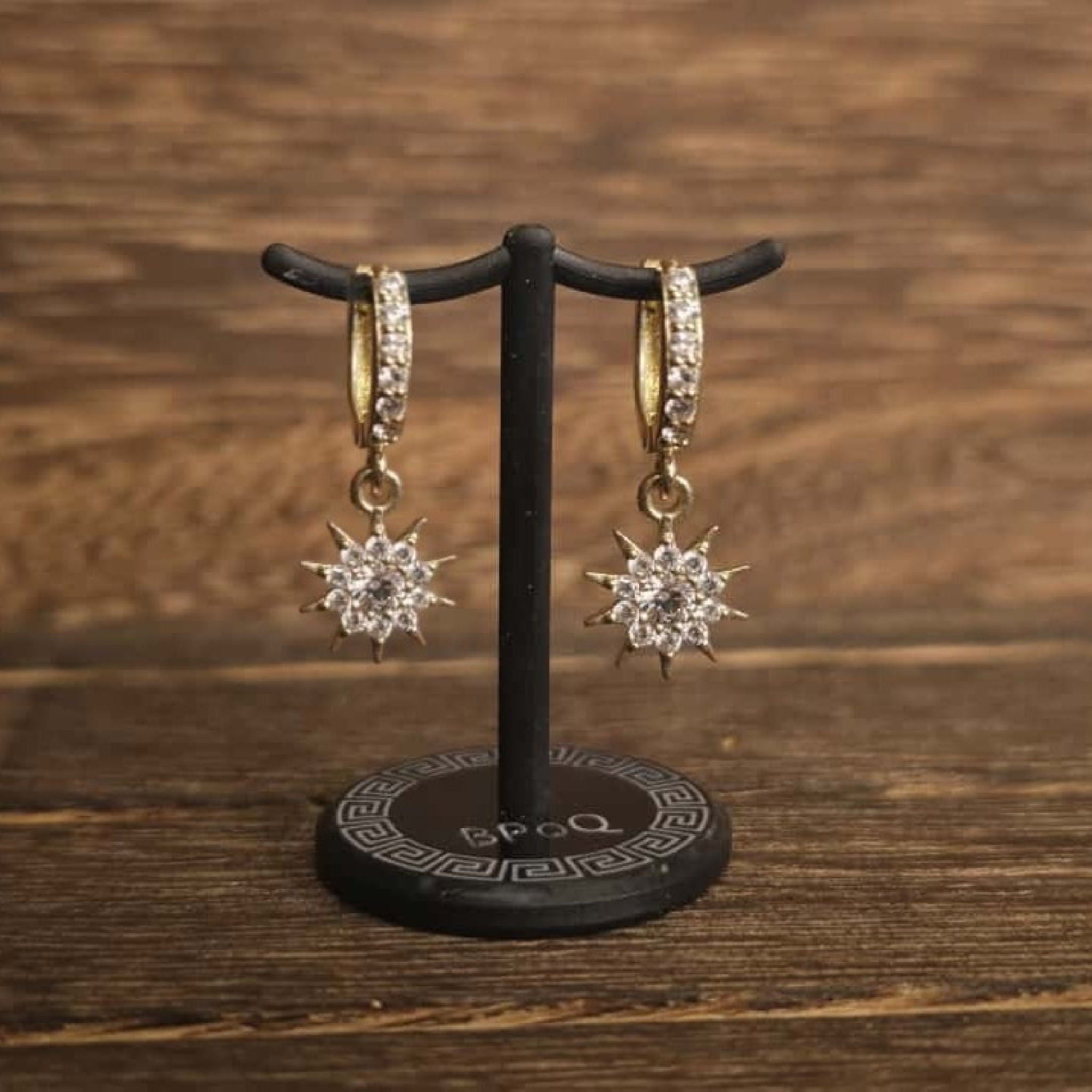 14K gold sunburst pave huggie earrings on display stand – Black Pearl of Queens