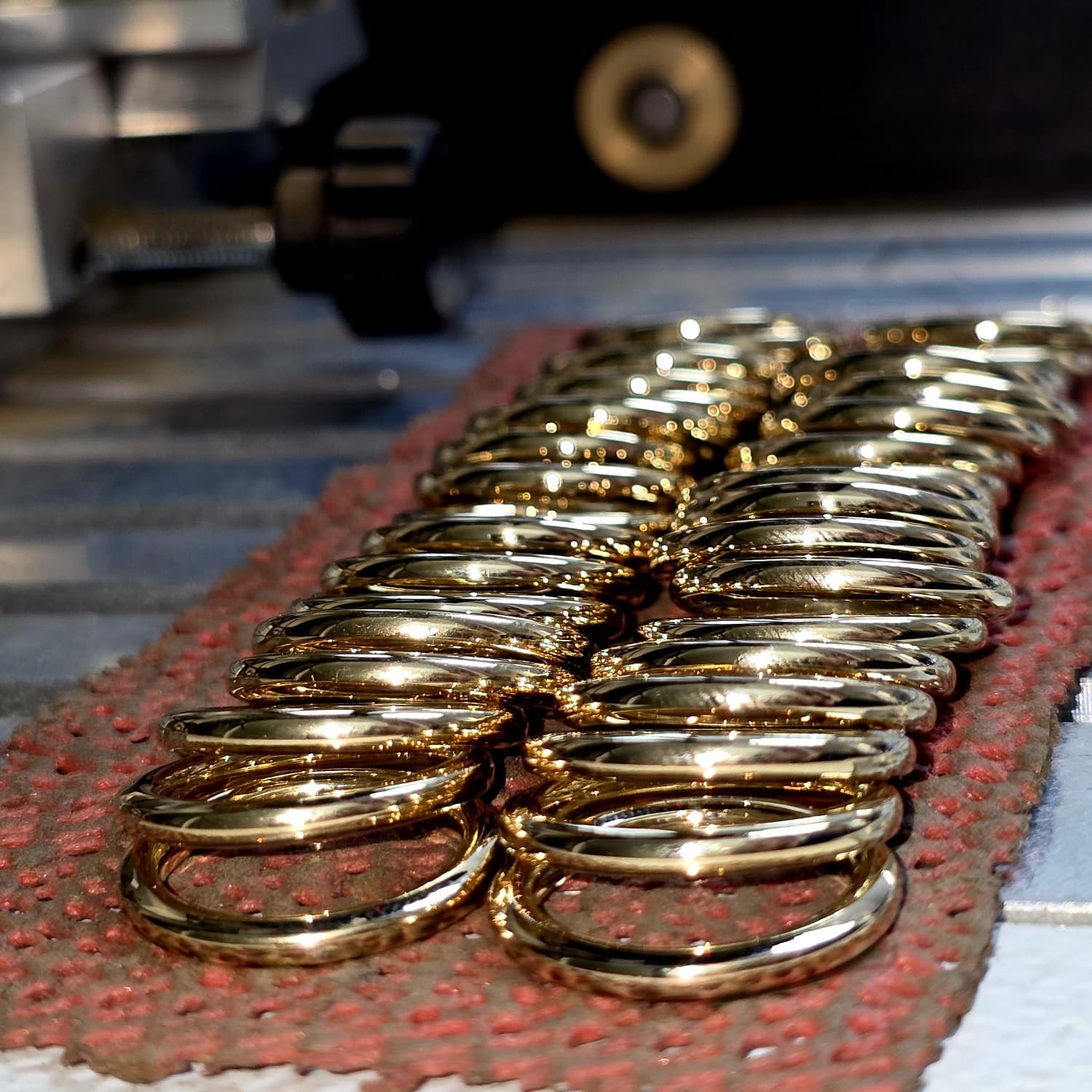 Rows of polished thin 14K gold wedding bands being hand-finished in a New York jewelry studio