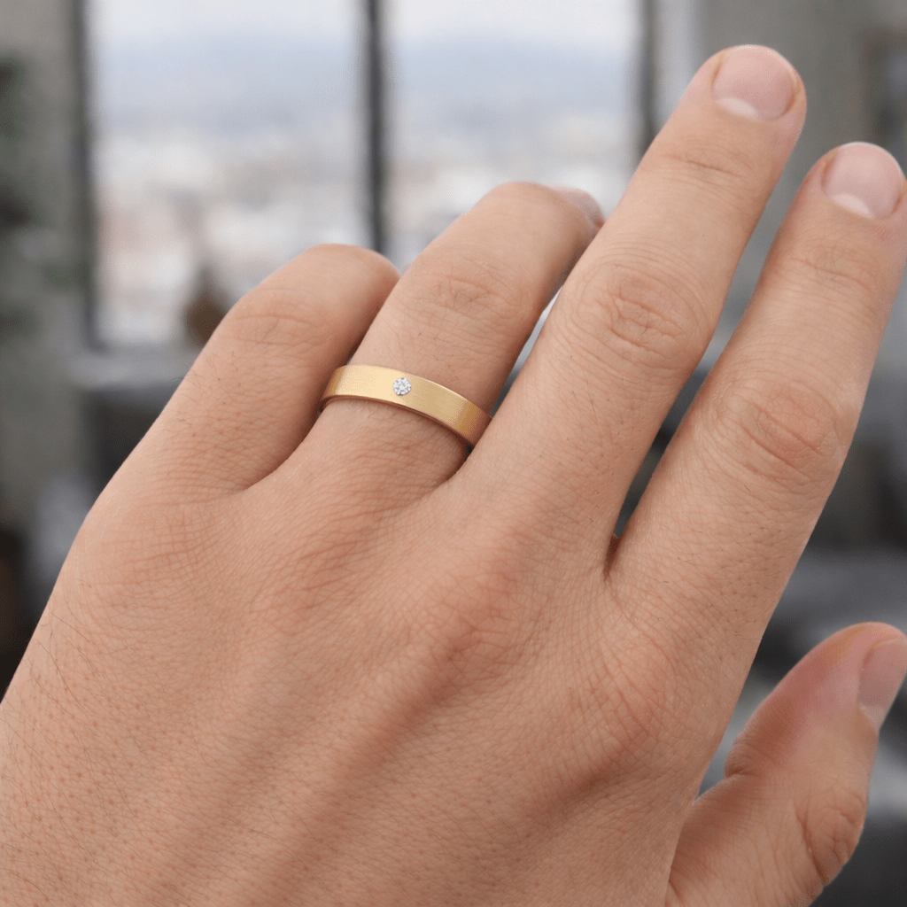 Men wearing a 5mm satin finished 14K yellow gold wedding band with a flush-set 0.10ct round diamond