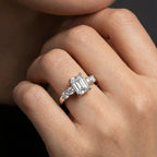Valen emerald diamond ring worn on hand featuring emerald cut center diamond and round side stones