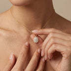 Woman wearing Valeria halo pendant necklace in 14K yellow gold with pear-shaped diamond and halo setting