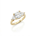Vela trilogy diamond engagement ring in 14k yellow gold featuring round center diamond with pear side stones, angled view