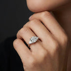 Close up of Vela trilogy diamond engagement ring showing round brilliant center diamond and pear side stones in prong setting