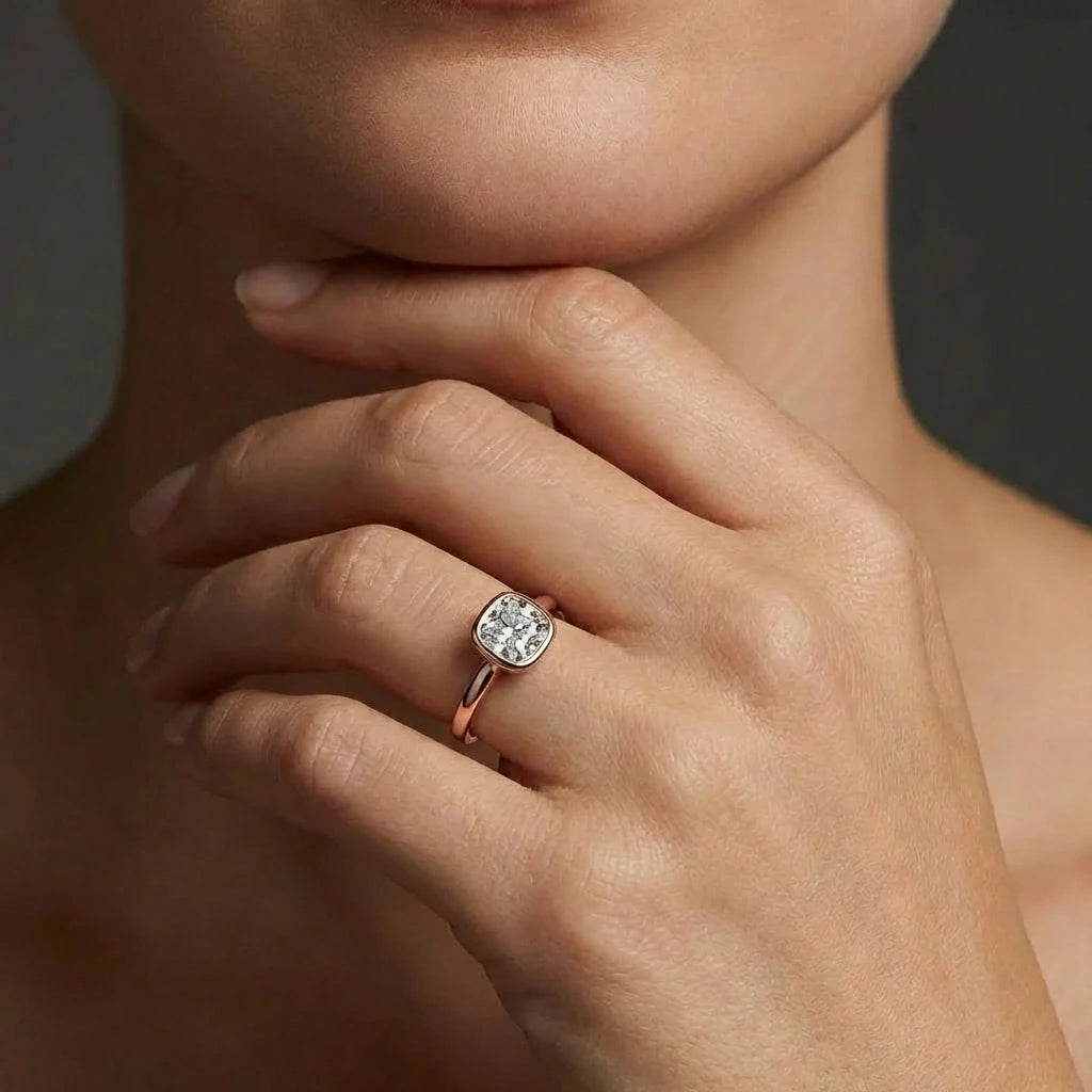 Model wearing cushion cut diamond ring in solid gold with bezel setting and refined minimalist design