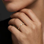 Female model wearing Virel Baguette Diamond Half Eternity Band in 14K yellow gold, close-up editorial shot showing horizontal baguette diamonds across top of band on finger