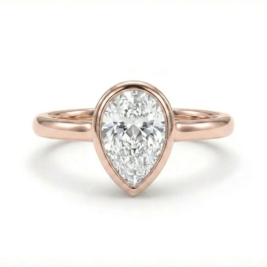 Solid 14K rose gold pear cut diamond ring with bezel set center stone and sleek band