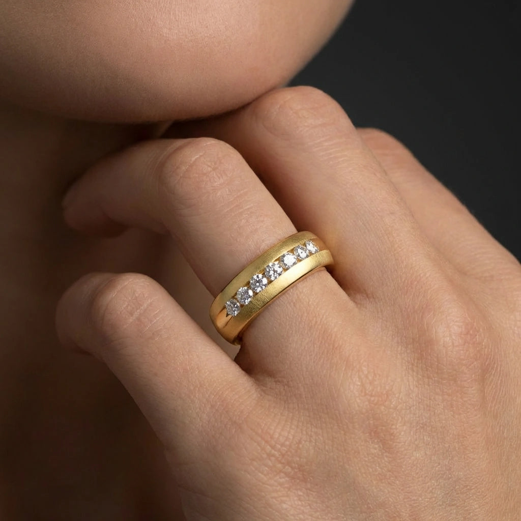 Close-up of 6mm Whitestone channel set diamond band in 14K yellow gold worn on hand