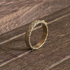 Handcrafted woven gold wedding ring photographed on wooden background