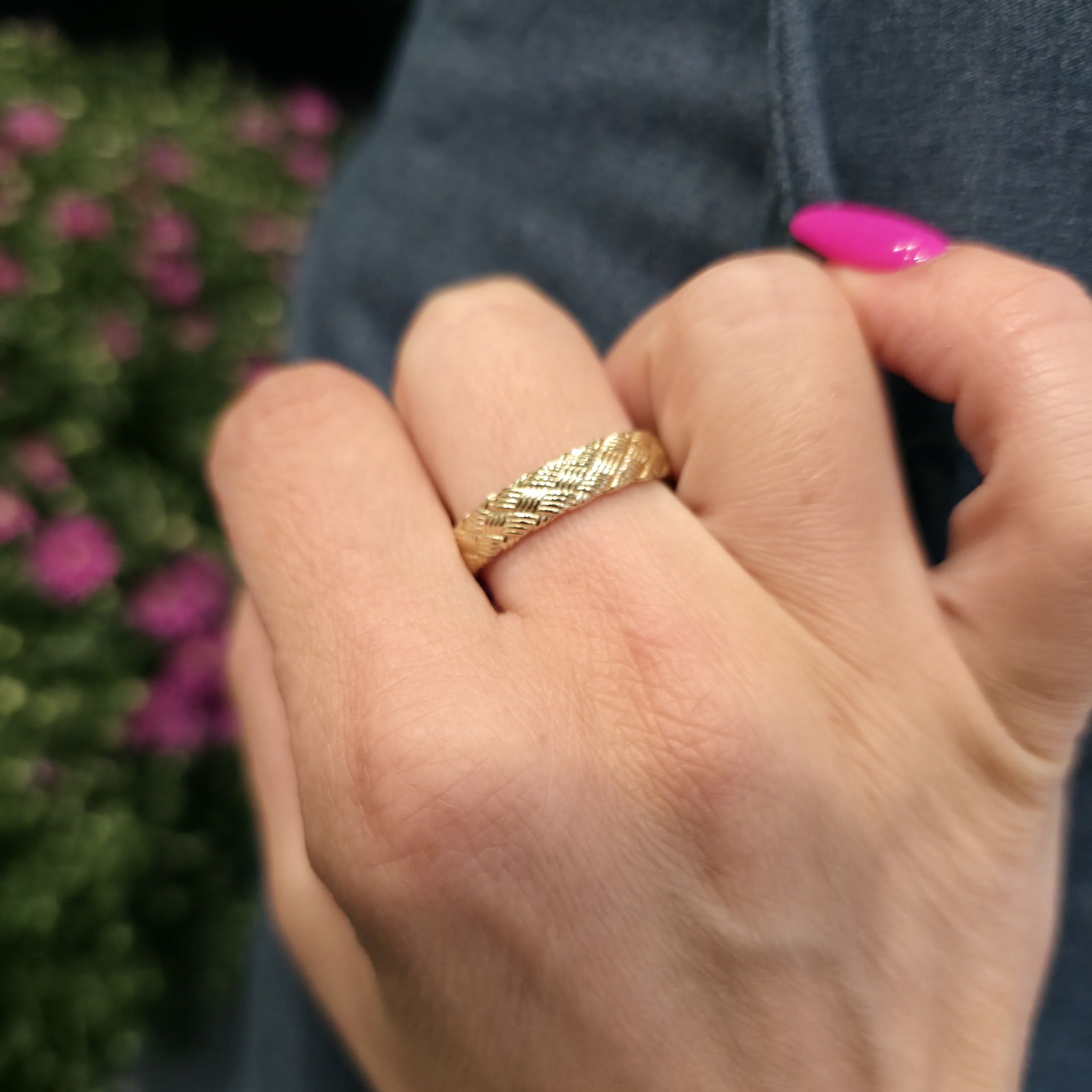 Woven gold wedding ring on a woman’s hand highlighting woven basket design